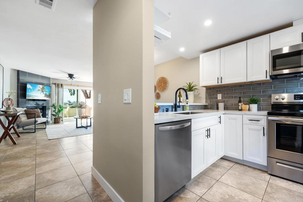 132 South Jayton Lane Encinitas, CA 92024 - Photo 4 of 37 a kitchen with stainless steel appliances granite countertop a refrigerator oven a sink dishwasher and white cabinets with wooden floor