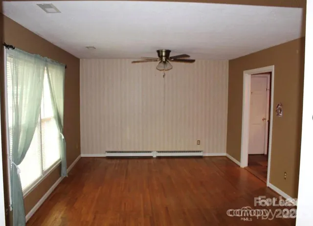 a view of room with hardwood floor and a ceiling fan