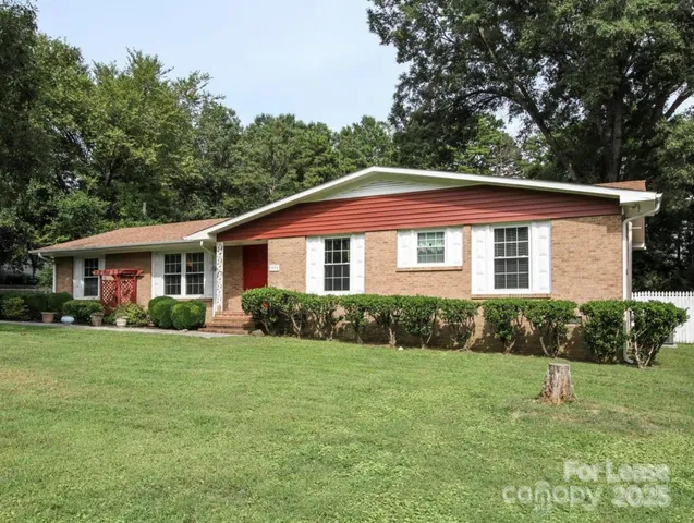 a view of a yard in front of a house with plants and large tree