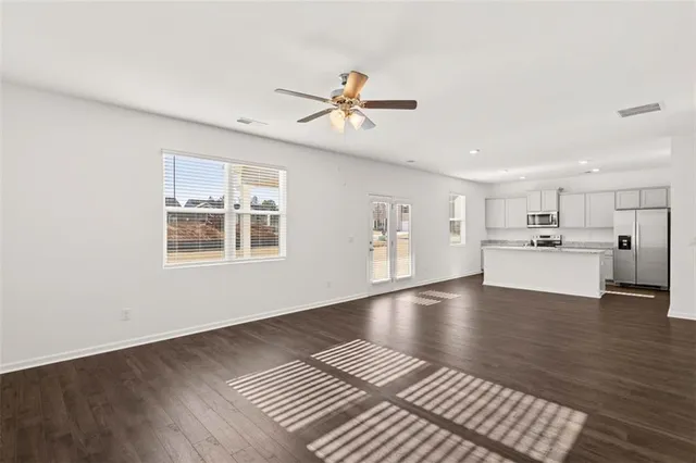 a view of an empty room with window and wooden floor