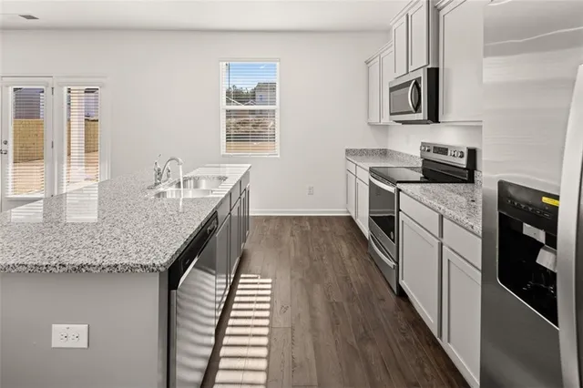 a kitchen with granite countertop stainless steel appliances sink stove and cabinets