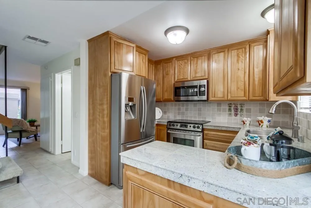 8918 Fletcher Valley Dr. Santee, CA 92071 - Photo 11 of 31 a kitchen with granite countertop wooden cabinets a refrigerator and a stove top oven