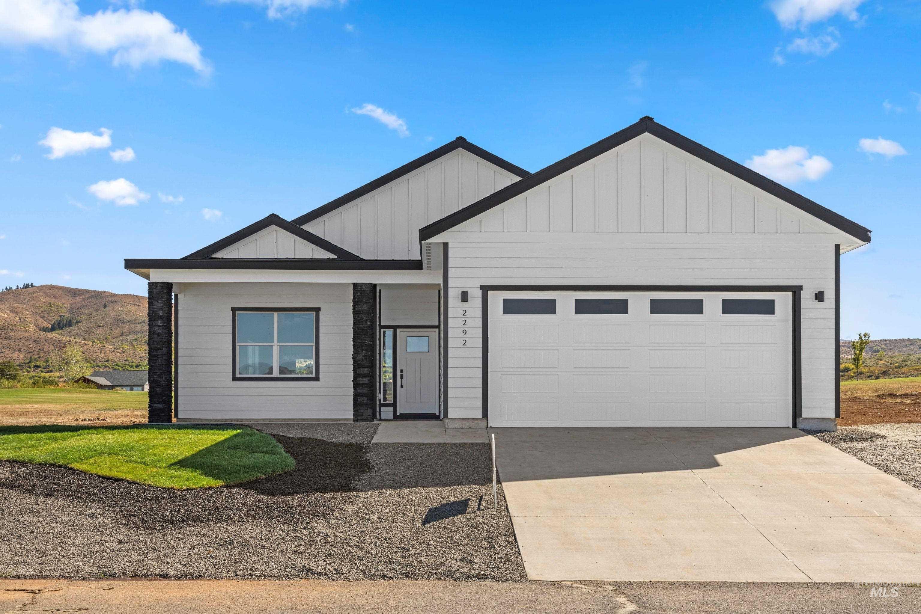 New construction single-level home in Council, Idaho featuring modern farmhouse design, clean white exterior, attached two-car garage, fresh landscaping, paved driveway, and wide-open mountain views in a quiet rural setting.