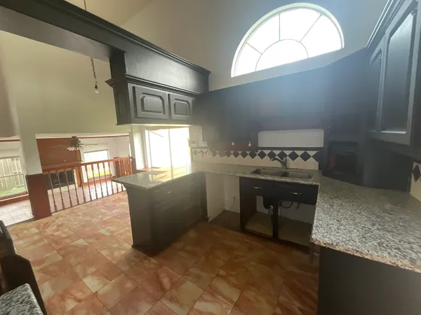 a kitchen with a stove a refrigerator and countertop dining table with wooden floor