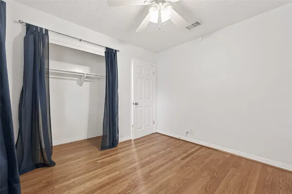 an empty room with wooden floor and a flat screen tv