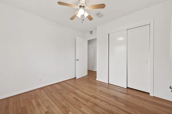 a view of an empty room and chandelier fan