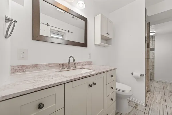 a bathroom with a granite countertop toilet sink and mirror