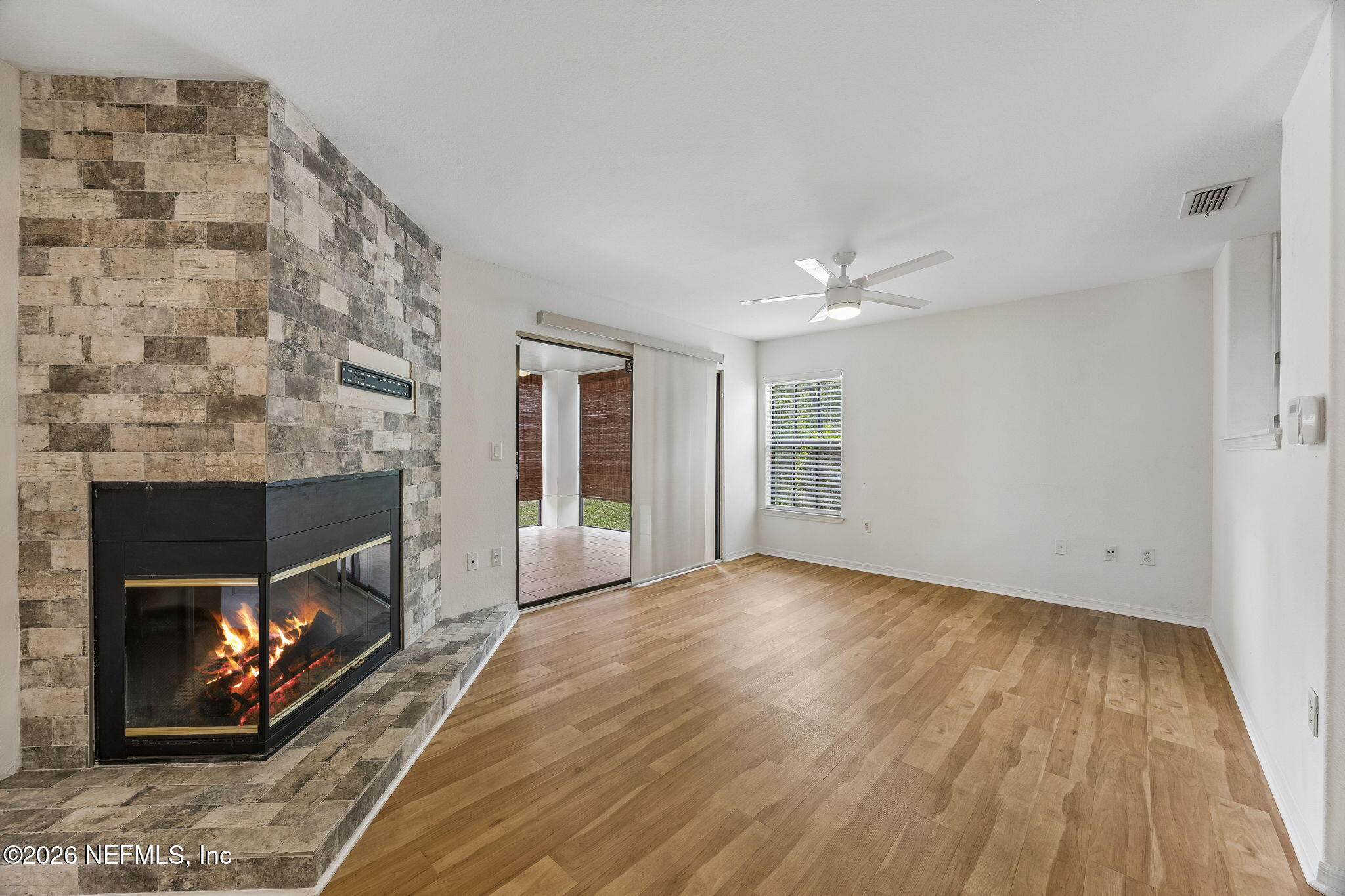 a view of an empty room with wooden floor fireplace and a window