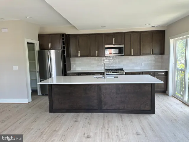 a kitchen with kitchen island stainless steel appliances a sink and refrigerator