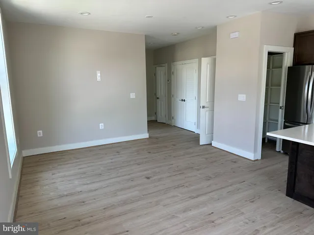 a view of an empty room with wooden floor and a cabinet