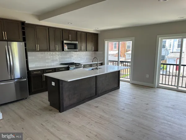 a kitchen with stainless steel appliances granite countertop a stove a sink dishwasher a refrigerator and a microwave oven with wooden floor