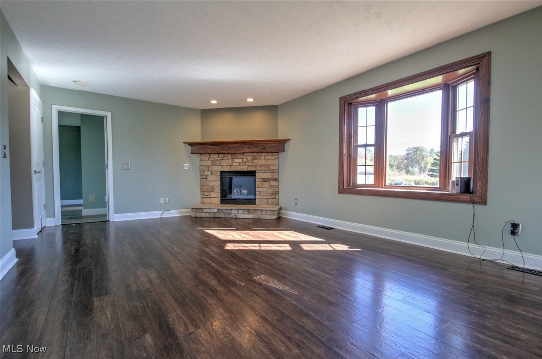 4998 Wayne Road Mantua, OH 44255 - Photo 12 of 43 Unfurnished living room featuring dark wood-type flooring and a stone fireplace
