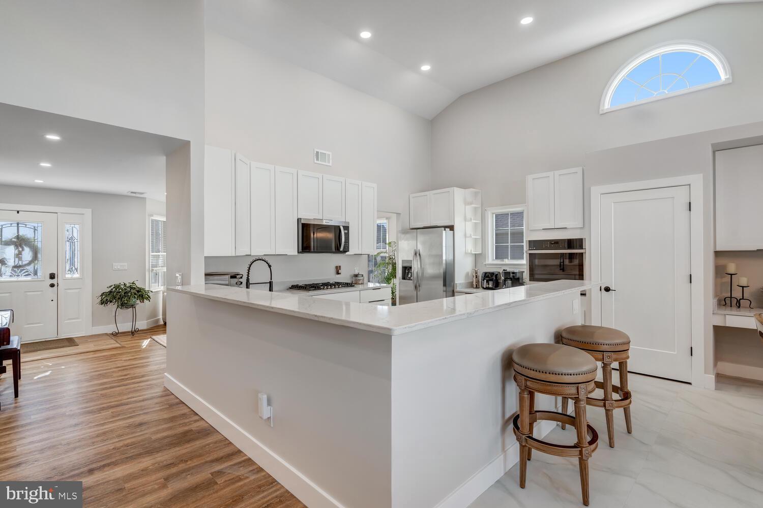 148 Compass Road Manahawkin, NJ 08050 - Photo 22 of 40 a kitchen with stainless steel appliances kitchen island a refrigerator and a stove top oven with white cabinets