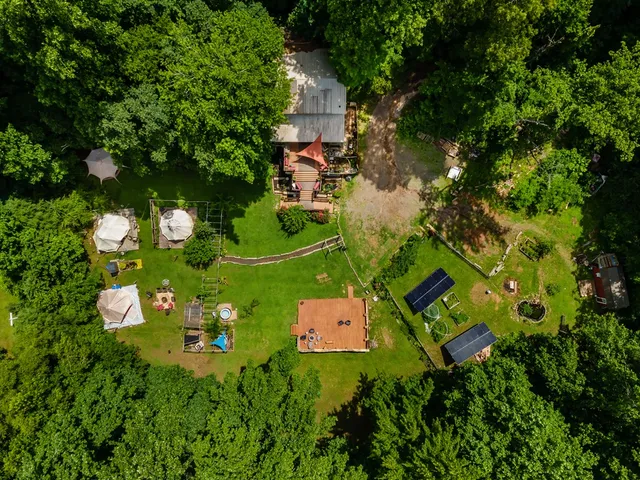 an aerial view of residential house with outdoor space and trees all around
