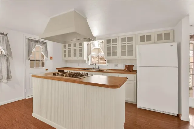 a kitchen with stainless steel appliances granite countertop a refrigerator a sink and white cabinets