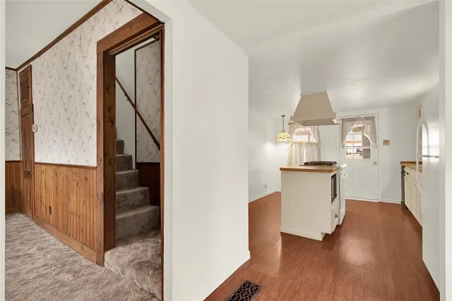 a view of a hallway with wooden floor and a bathroom