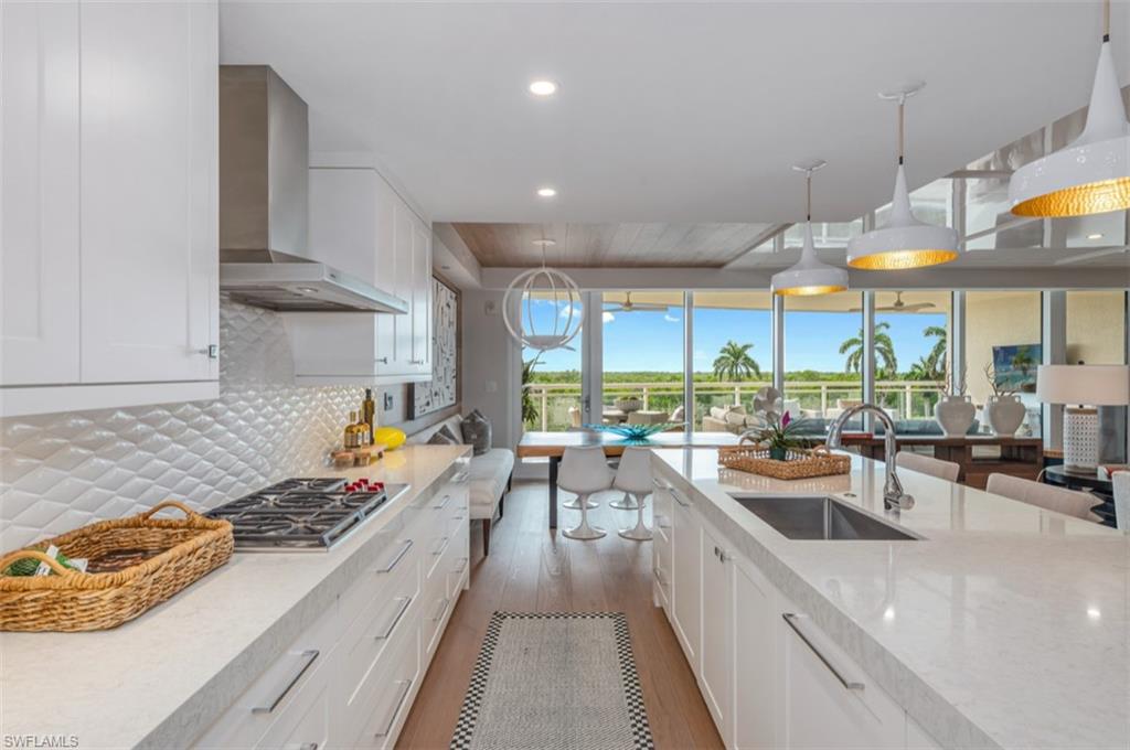 13925 Old Coast Road, Unit 403 Naples, FL 34110 - Photo 11 of 24 Kitchen with white cabinets, backsplash, wall chimney exhaust hood, decorative light fixtures, and recessed lighting