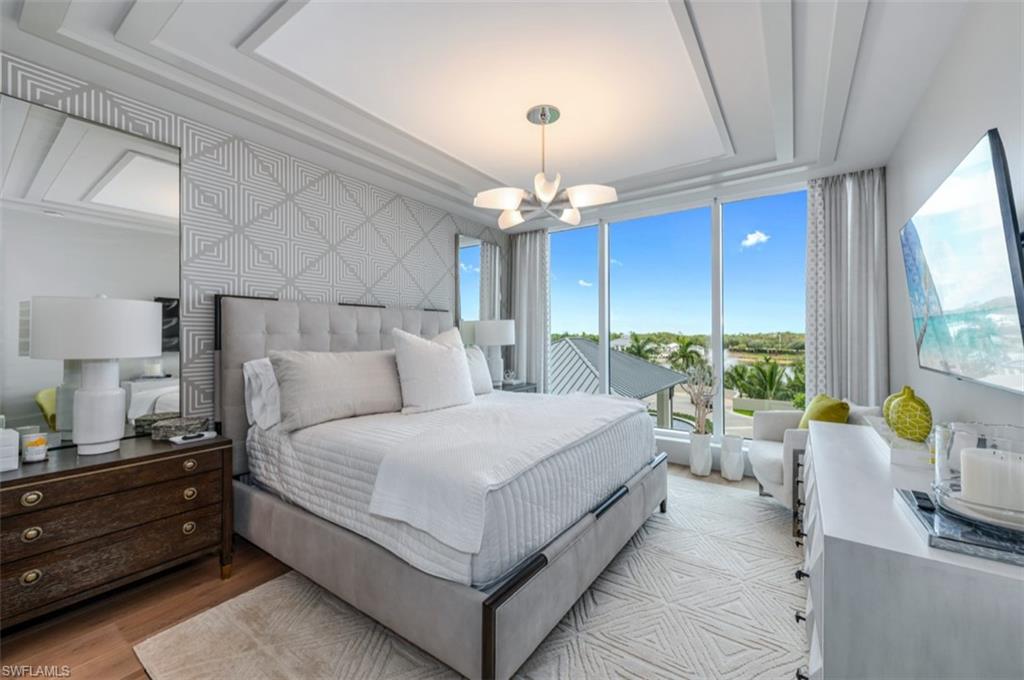 13925 Old Coast Road, Unit 403 Naples, FL 34110 - Photo 13 of 24 Bedroom with wood finished floors, a chandelier, and a tray ceiling