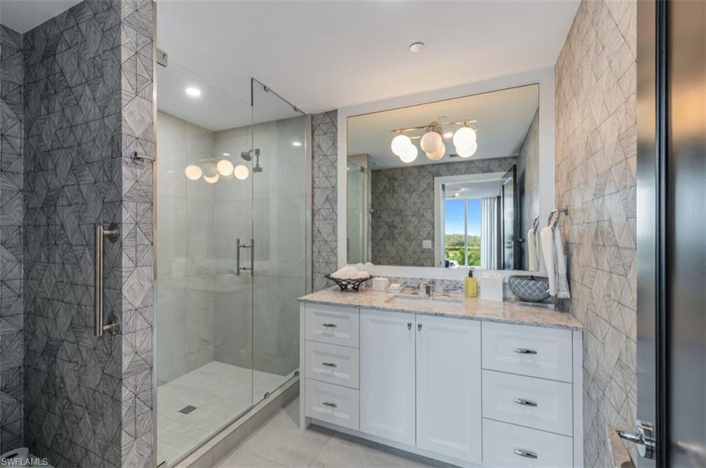 13925 Old Coast Road, Unit 403 Naples, FL 34110 - Photo 16 of 24 Bathroom with vanity, tile walls, a shower stall, and light tile patterned flooring