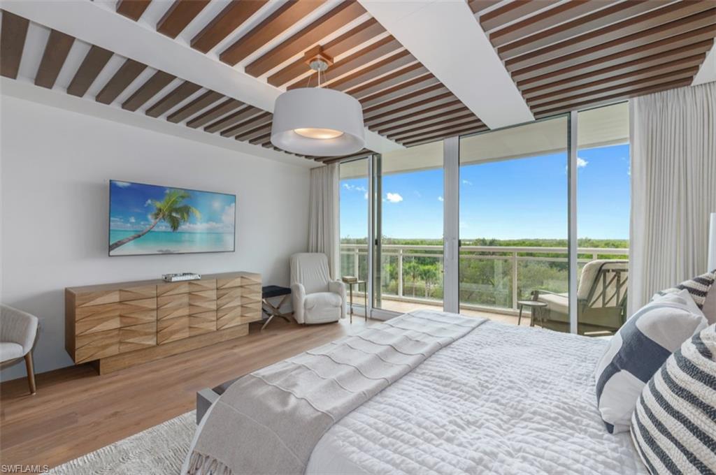 13925 Old Coast Road, Unit 403 Naples, FL 34110 - Photo 21 of 24 Bedroom with floor to ceiling windows, wood finished floors, and access to outside