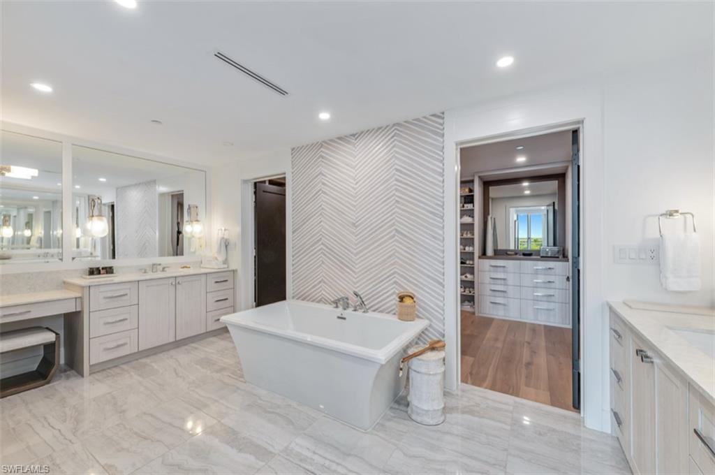 13925 Old Coast Road, Unit 403 Naples, FL 34110 - Photo 22 of 24 Bathroom with two vanities, a soaking tub, light marble finish floors, and recessed lighting