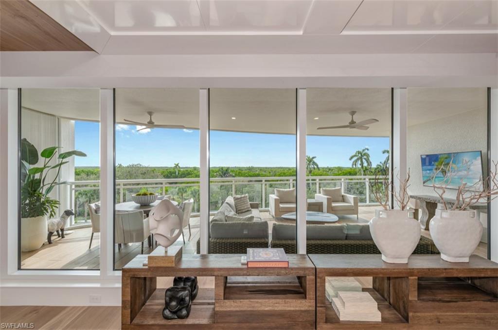13925 Old Coast Road, Unit 403 Naples, FL 34110 - Photo 8 of 24 Living area with wood finished floors, ceiling fan, healthy amount of natural light, and a wall of windows