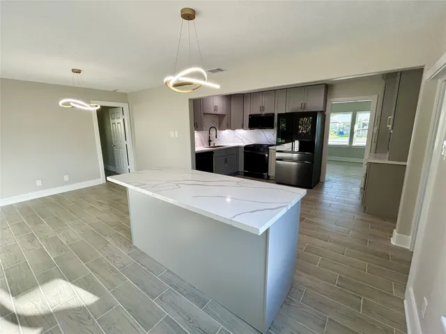 a large kitchen with kitchen island a sink stainless steel appliances and cabinets