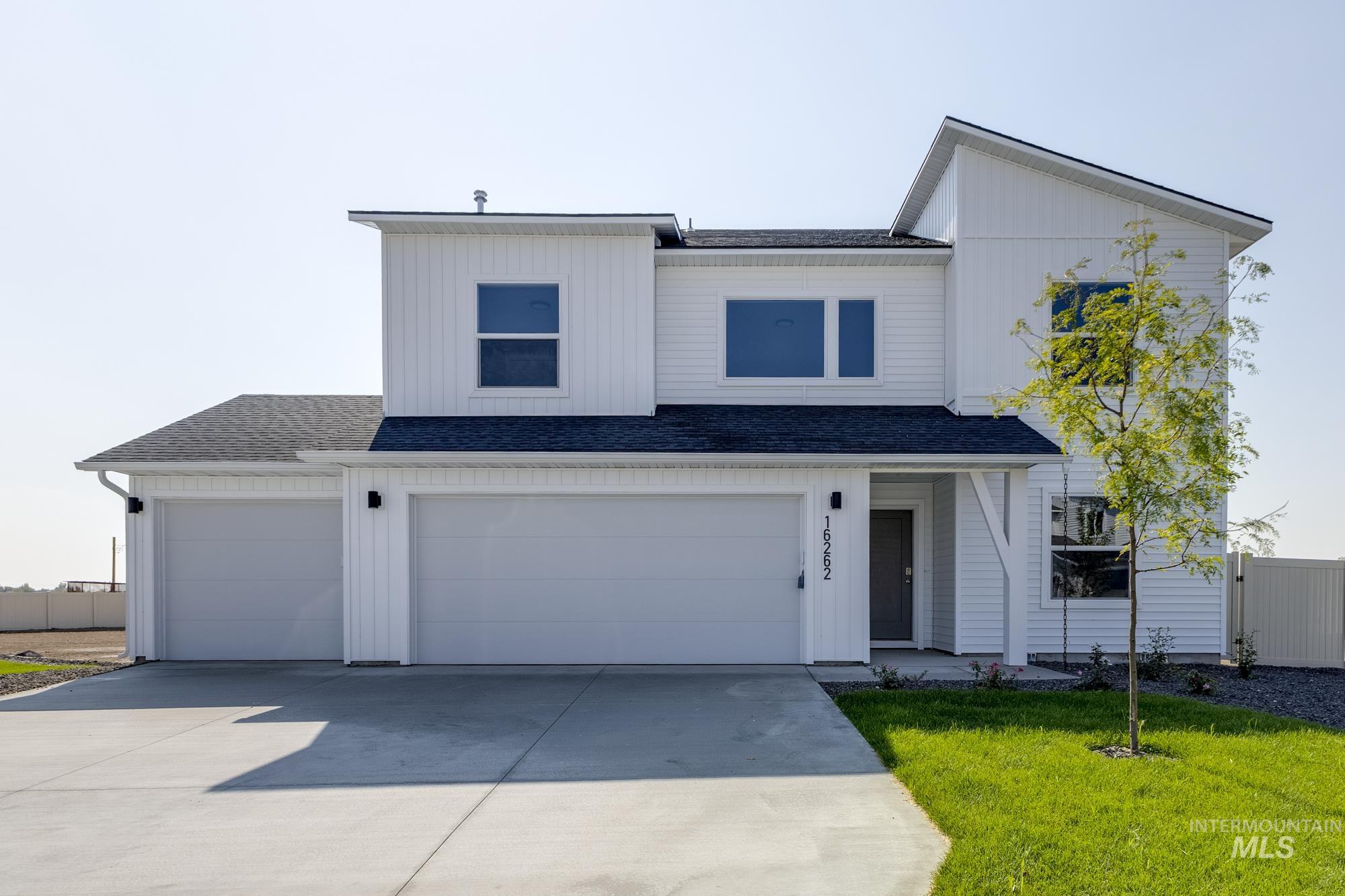 View of front facade featuring driveway, roof with shingles, and an attached garage
