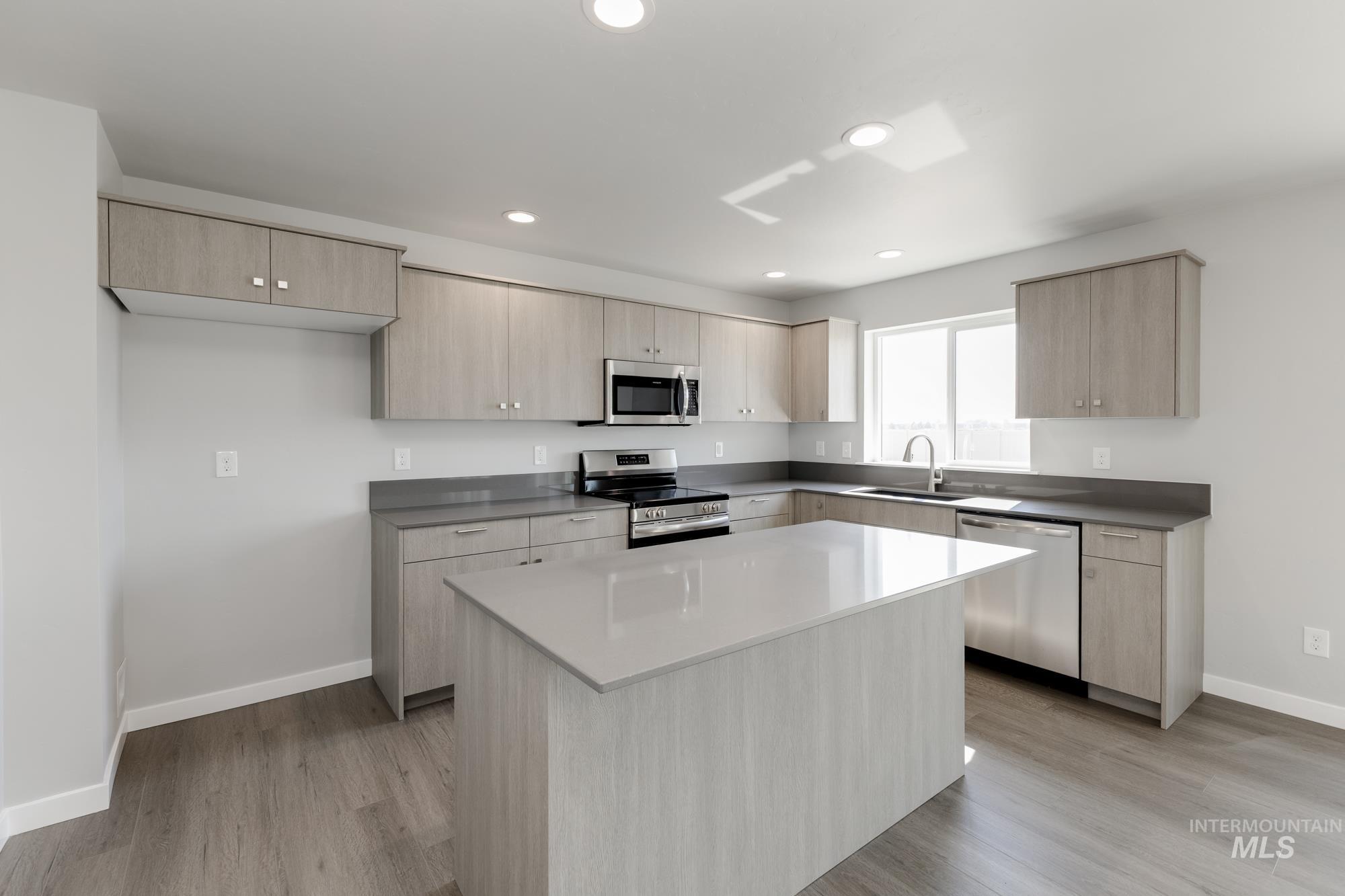 16262 Backfill Place Caldwell, ID 83607 - Photo 4 of 25 Kitchen with light brown cabinetry, modern cabinets, appliances with stainless steel finishes, light wood-style floors, and a center island