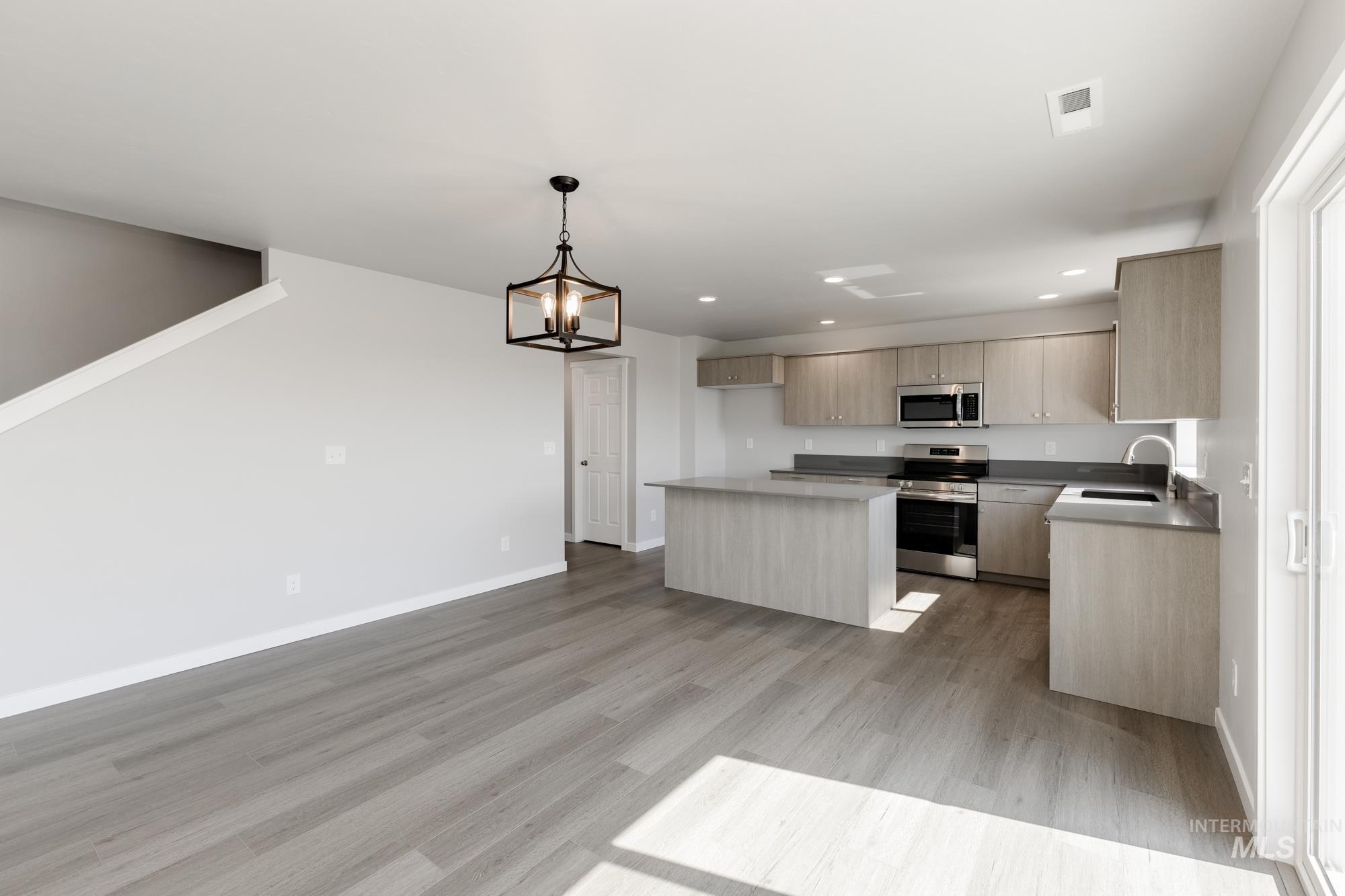 16262 Backfill Place Caldwell, ID 83607 - Photo 7 of 25 Kitchen featuring appliances with stainless steel finishes, a kitchen island, decorative light fixtures, modern cabinets, and a chandelier