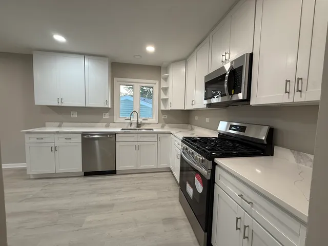 a kitchen with stainless steel appliances granite countertop a stove a sink and a microwave
