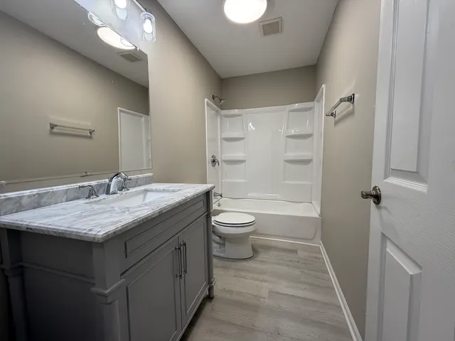 a bathroom with a granite countertop sink toilet and shower