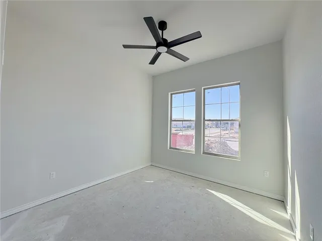an empty room with ceiling fan and windows