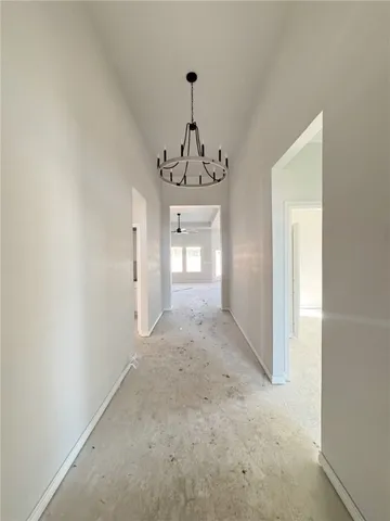 a view of a hallway with wooden floor and a chandelier