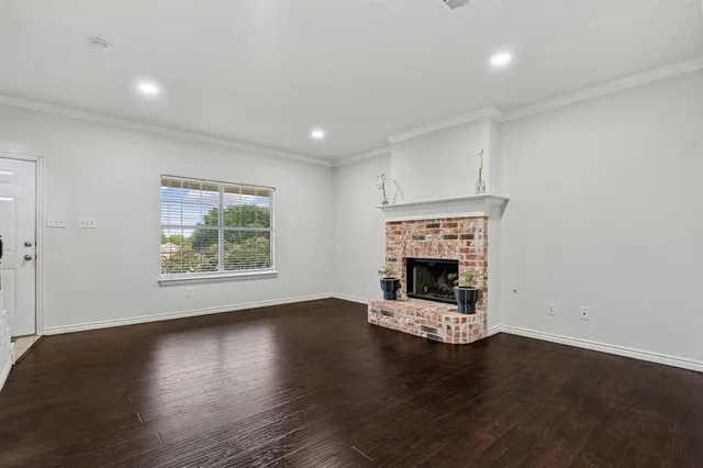 an empty room with wooden floor fireplace and windows