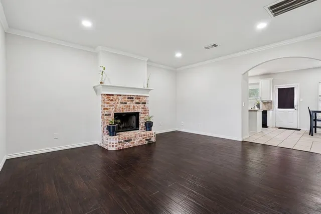 a view of an empty room with wooden floor fireplace and a window