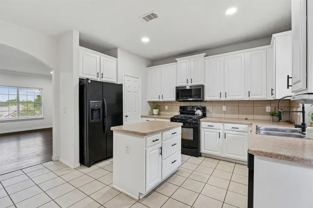 a kitchen with a refrigerator sink and cabinets