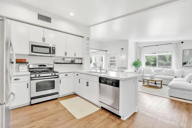 a kitchen with stainless steel appliances white cabinets a sink and a stove