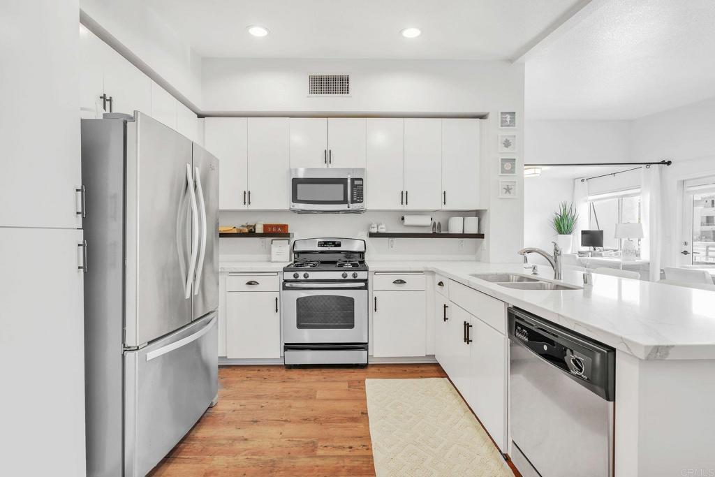687 South Coast Highway 101, Unit 302 Encinitas, CA 92024 - Photo 11 of 32 a kitchen with stainless steel appliances a refrigerator sink and microwave