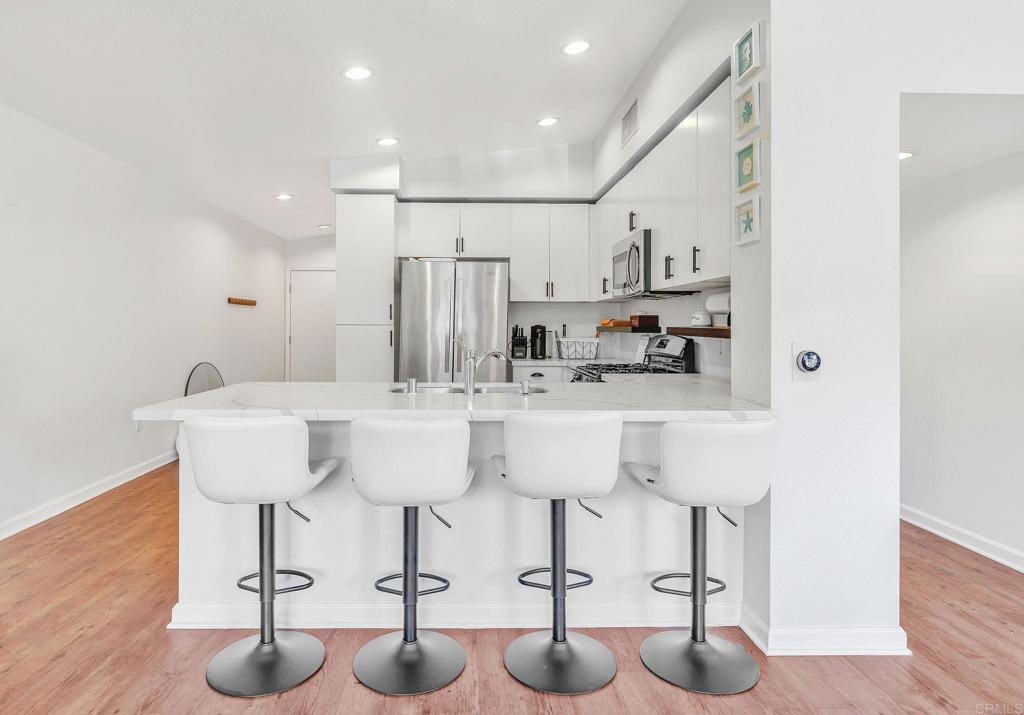 687 South Coast Highway 101, Unit 302 Encinitas, CA 92024 - Photo 9 of 32 a kitchen with cabinets and chairs