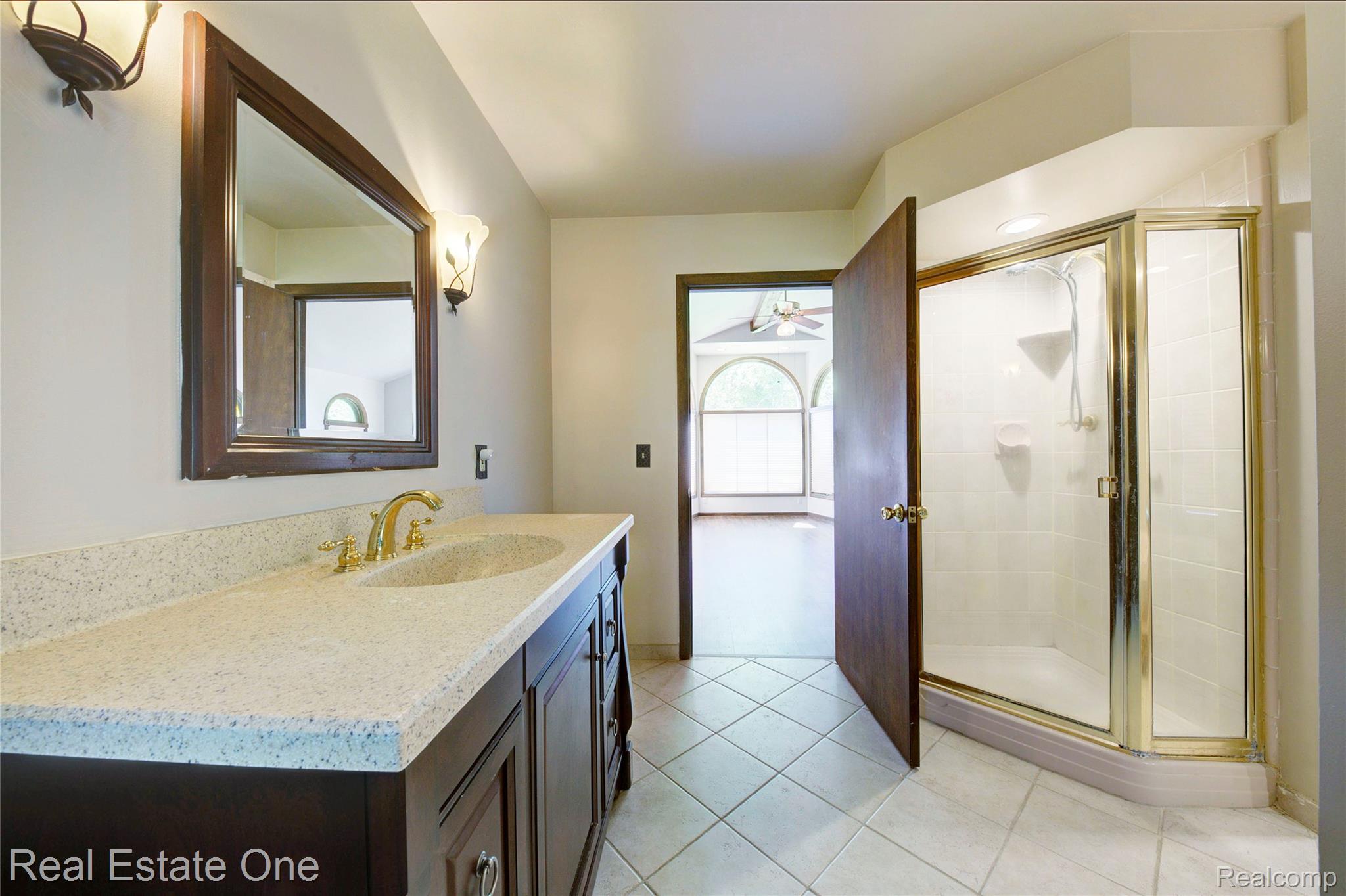 3125 West Commerce Road Milford, MI 48380 - Photo 33 of 63 Bathroom featuring a single vanity with a light-colored countertop and integrated sink, gold-toned faucet, and dark wood cabinetry
