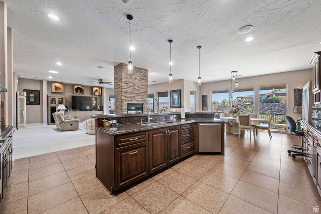 2376 Stone Crest Circle St. George, UT 84790 - Photo 61 of 61 Kitchen featuring dark wood finish cabinets, decorative light fixtures, open floor plan, a fireplace, and dark stone countertops