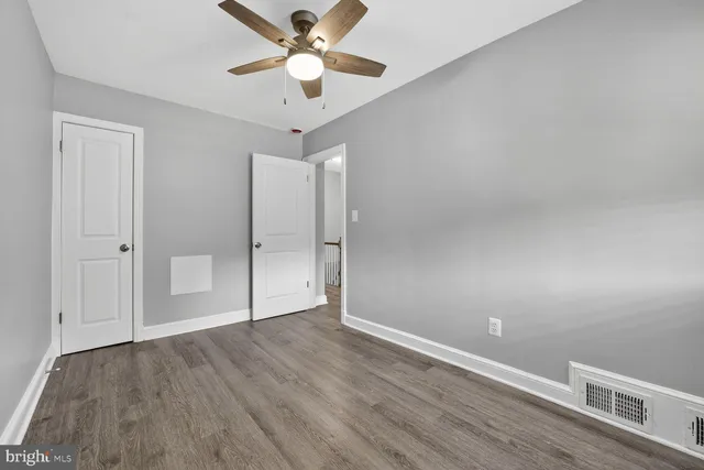 an empty room with wooden floor and a ceiling fan
