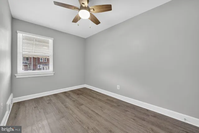 an empty room with wooden floor fan and windows