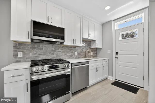 a kitchen with white cabinets and stainless steel appliances