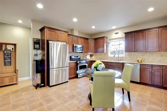 a kitchen with stainless steel appliances a refrigerator a stove a microwave a dining table and chairs