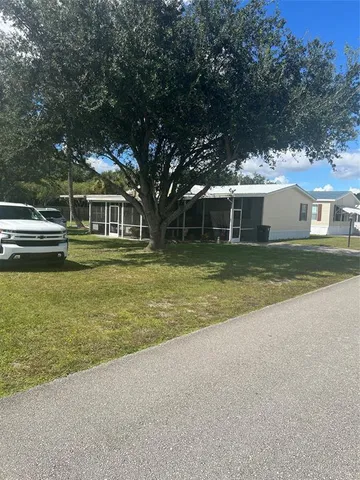 a view of a house with a big yard and large trees