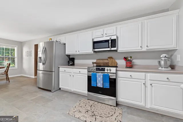 a kitchen with stainless steel appliances granite countertop a refrigerator stove a sink and white cabinets