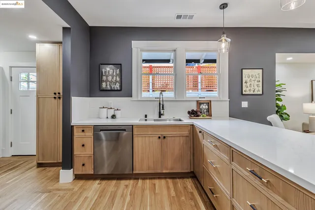 a kitchen with a sink dishwasher a stove and white cabinets with wooden floor
