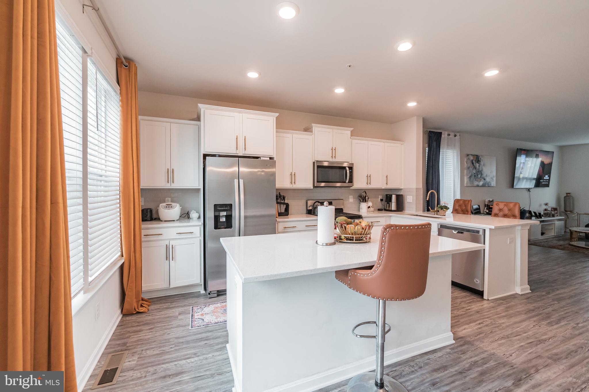 7041 Freedom Way Frederick, MD 21703 - Photo 2 of 32 a kitchen with stainless steel appliances granite countertop a refrigerator a stove top oven a sink dishwasher and white cabinets with wooden floor